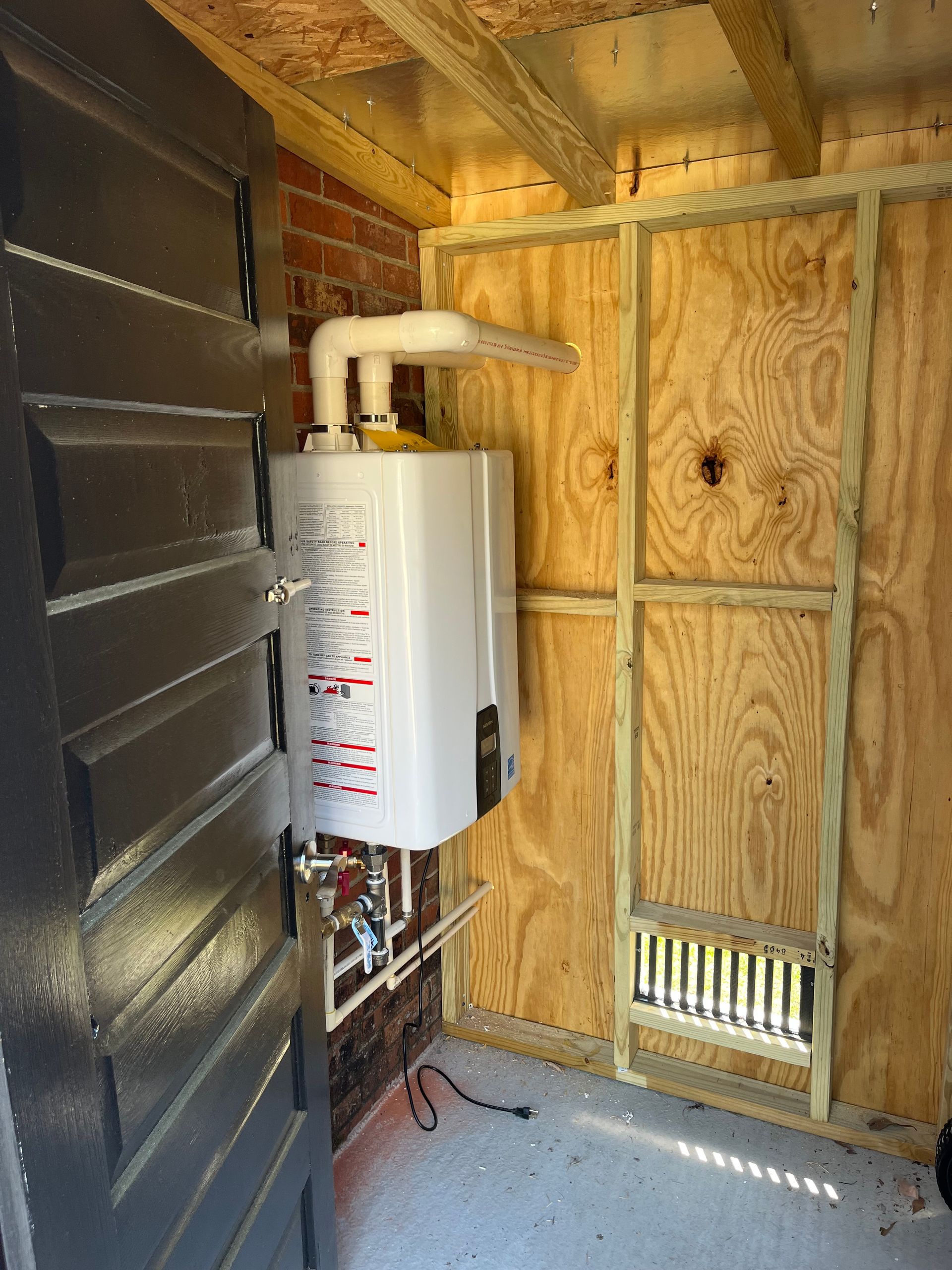 A white water heater is mounted to a wooden wall