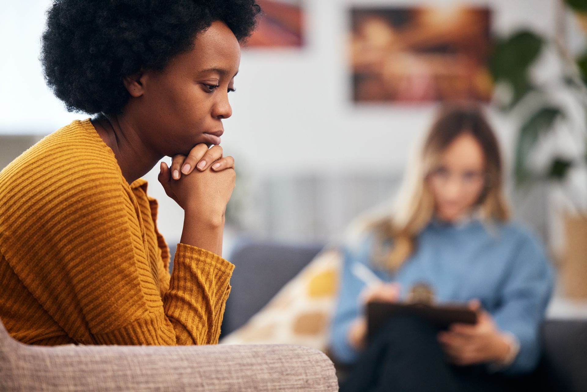 A woman is sitting on a couch talking to a therapist.