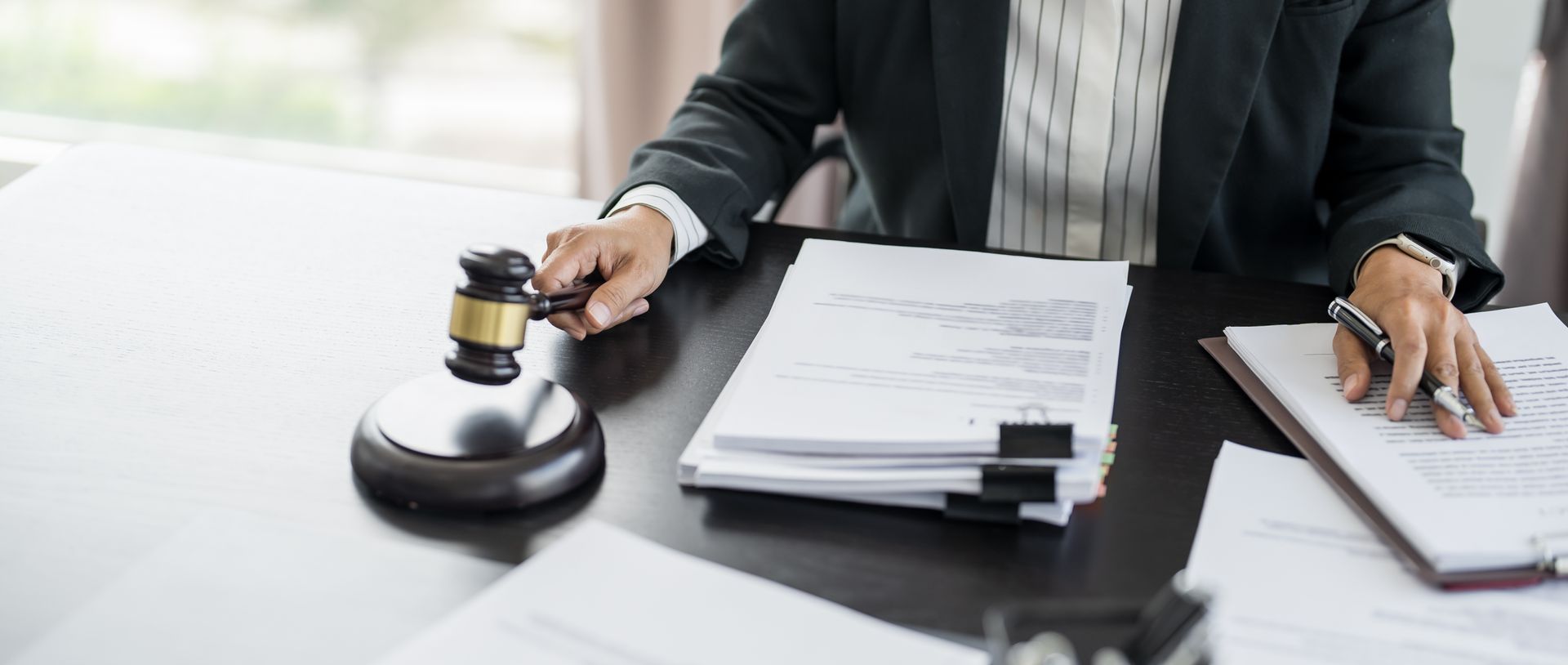 A judge is sitting at a desk holding a gavel.