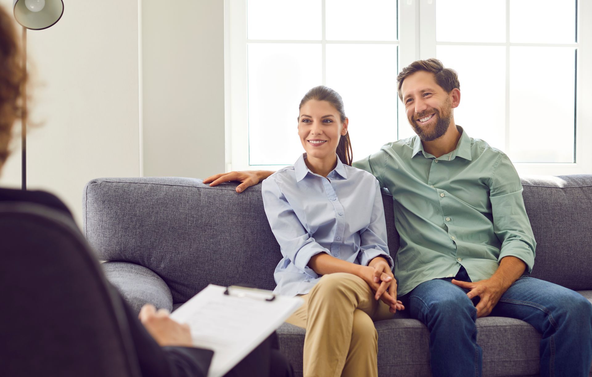 A man and a woman are sitting on a couch talking to a counselor.