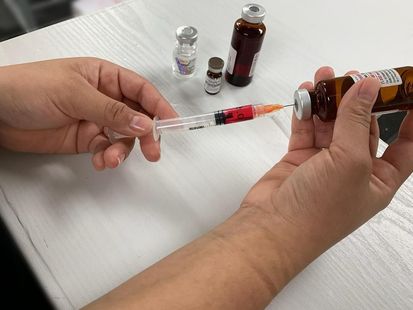 A person is holding a syringe and a bottle of liquid.