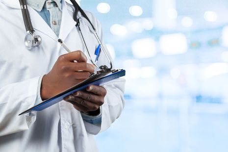 A doctor is writing weight loss results on a clipboard in a clinic.