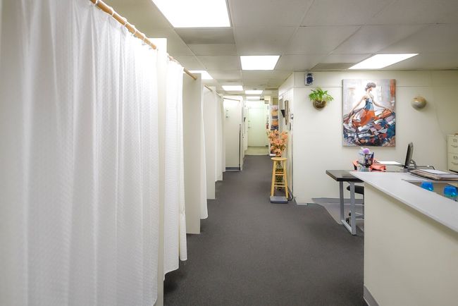 A long hallway with white curtains and a painting on the wall