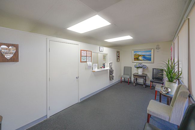 A waiting room with chairs , tables and a counter.