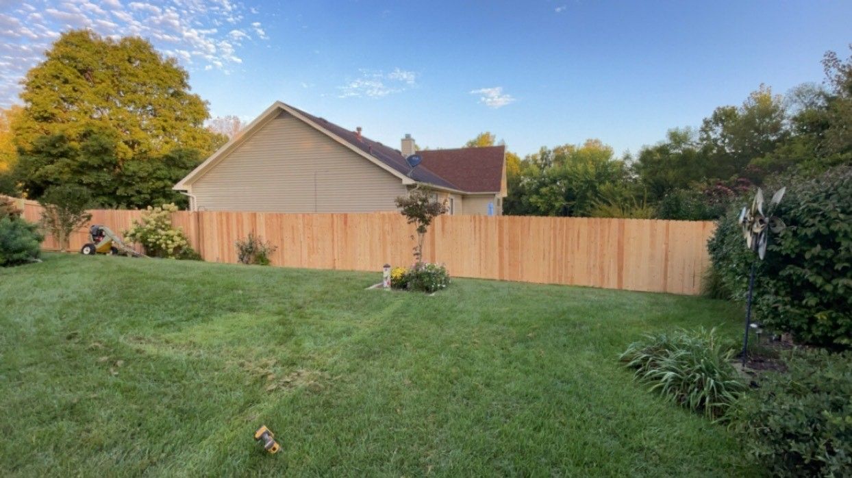A wooden fence surrounds a lush green lawn.