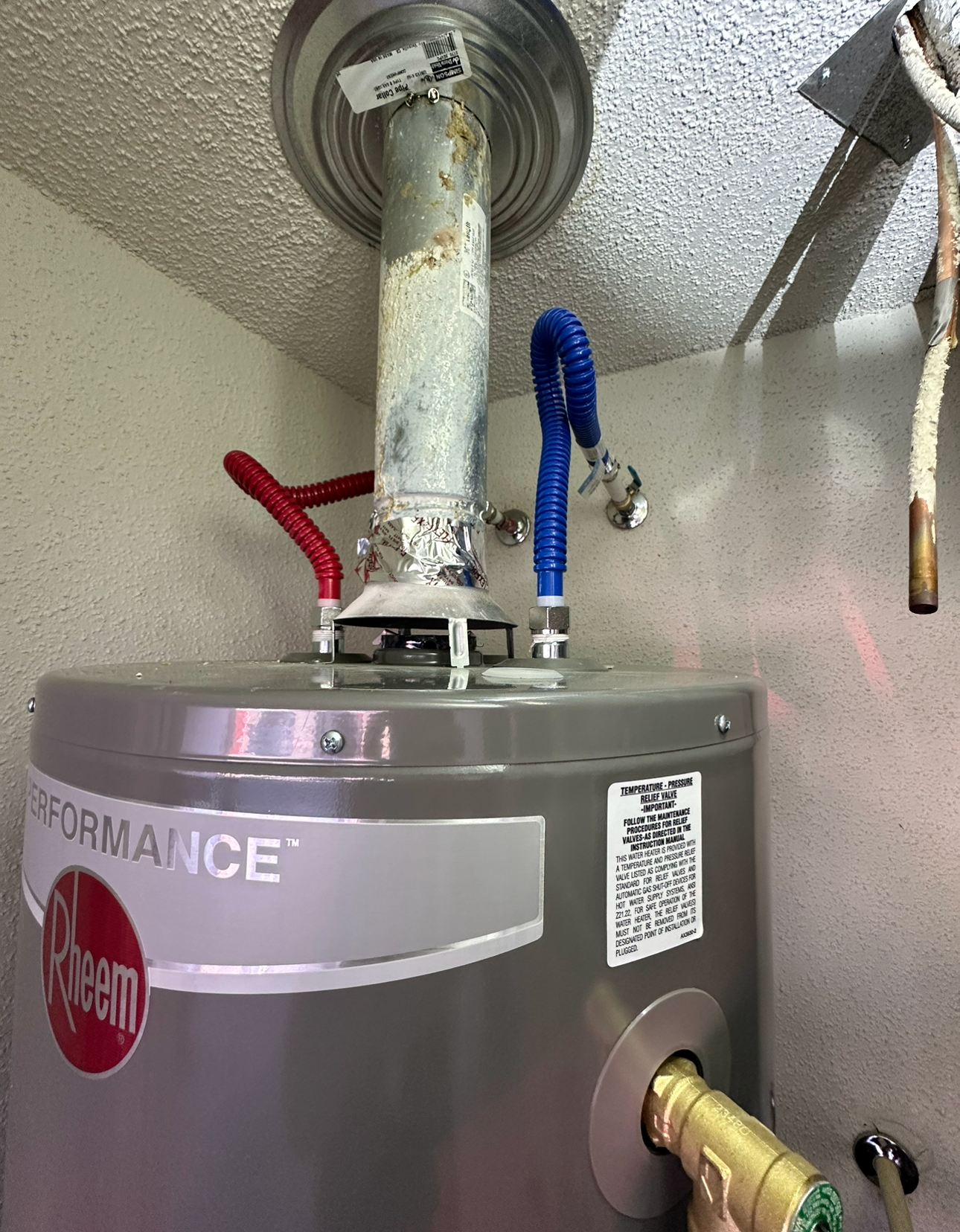 A rheem water heater is hanging from the ceiling