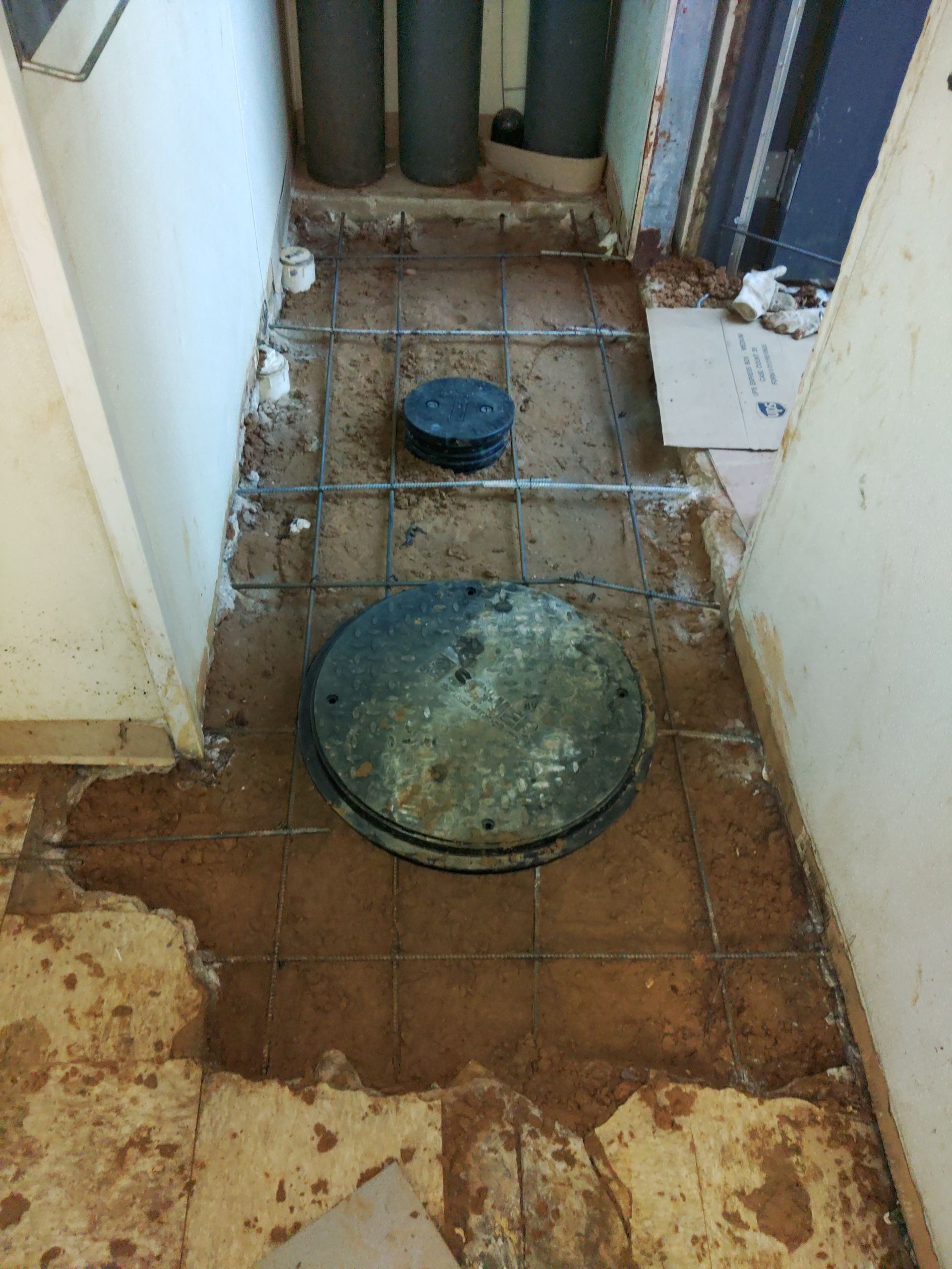 A manhole cover is sitting on a tiled floor in a room.