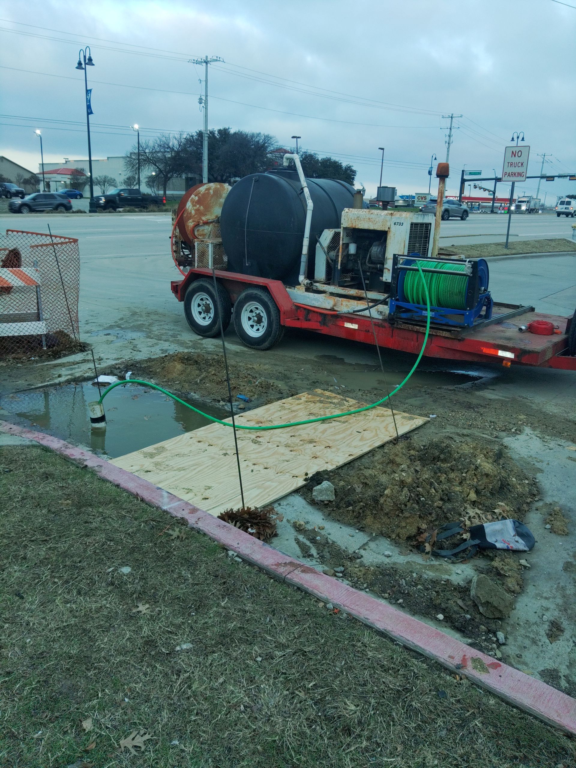A trailer with a hose attached to it is parked in a parking lot.