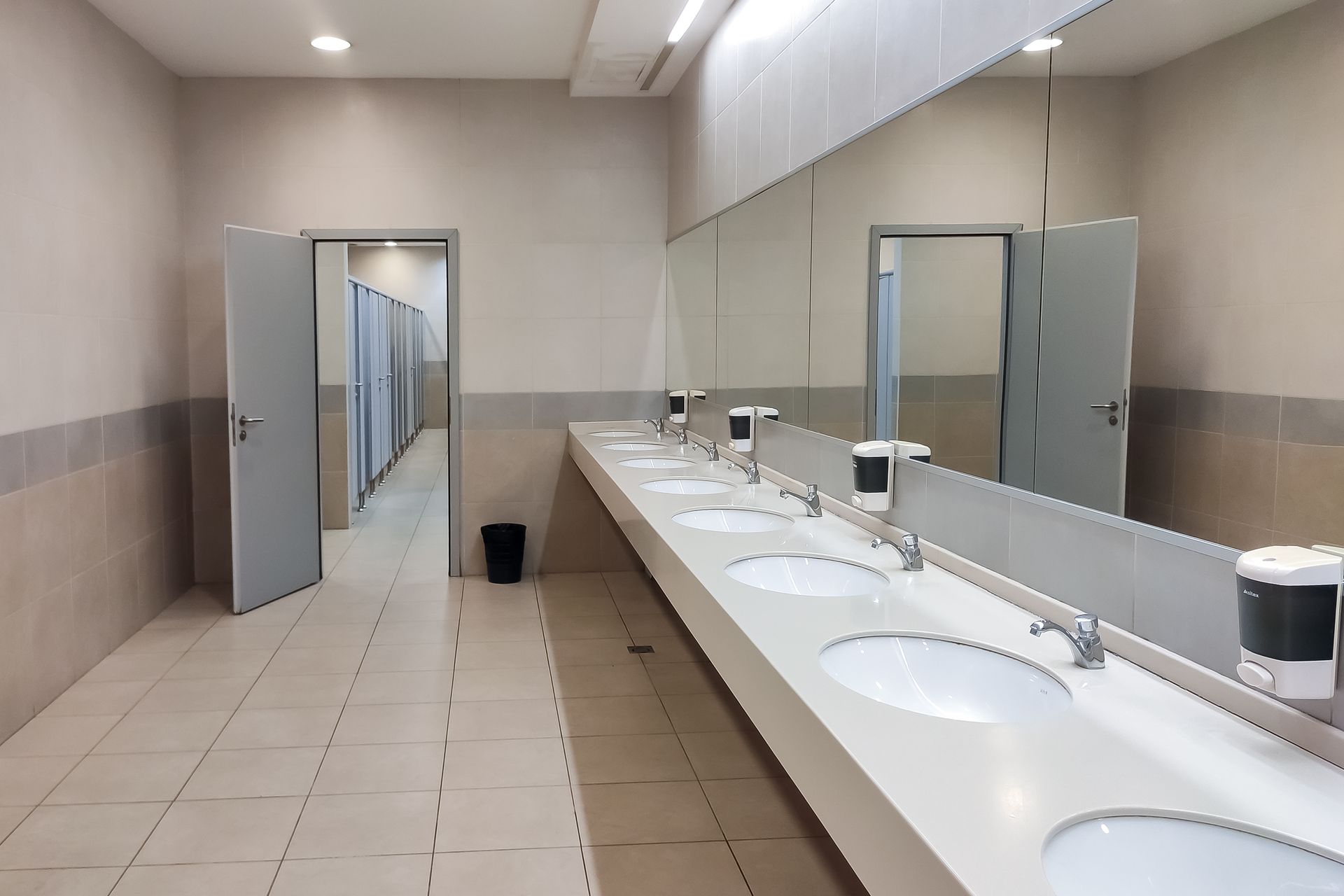 A public restroom with a long row of sinks and mirrors.
