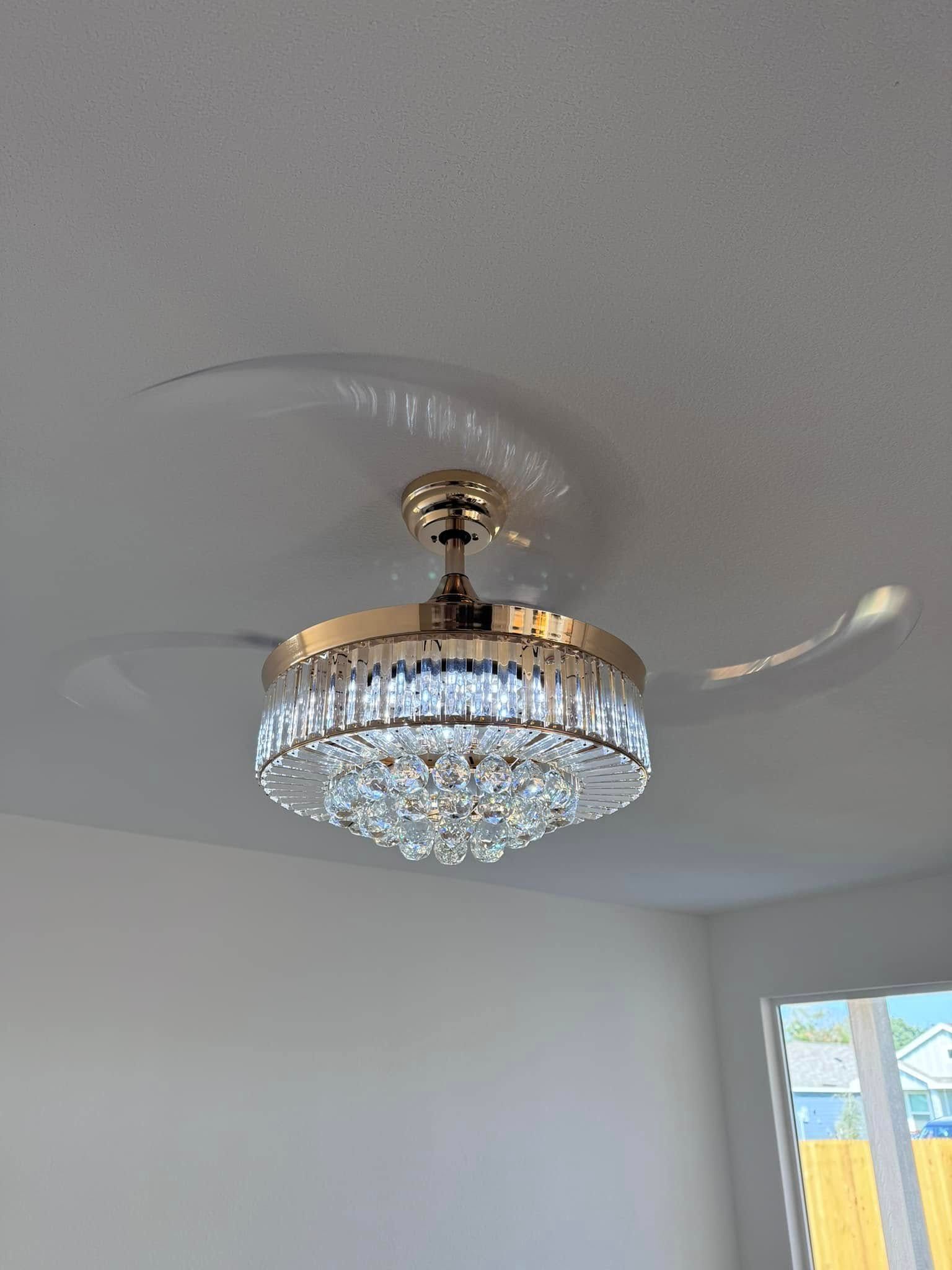 Gold and crystal ceiling fan with blades blurred by motion; white ceiling.