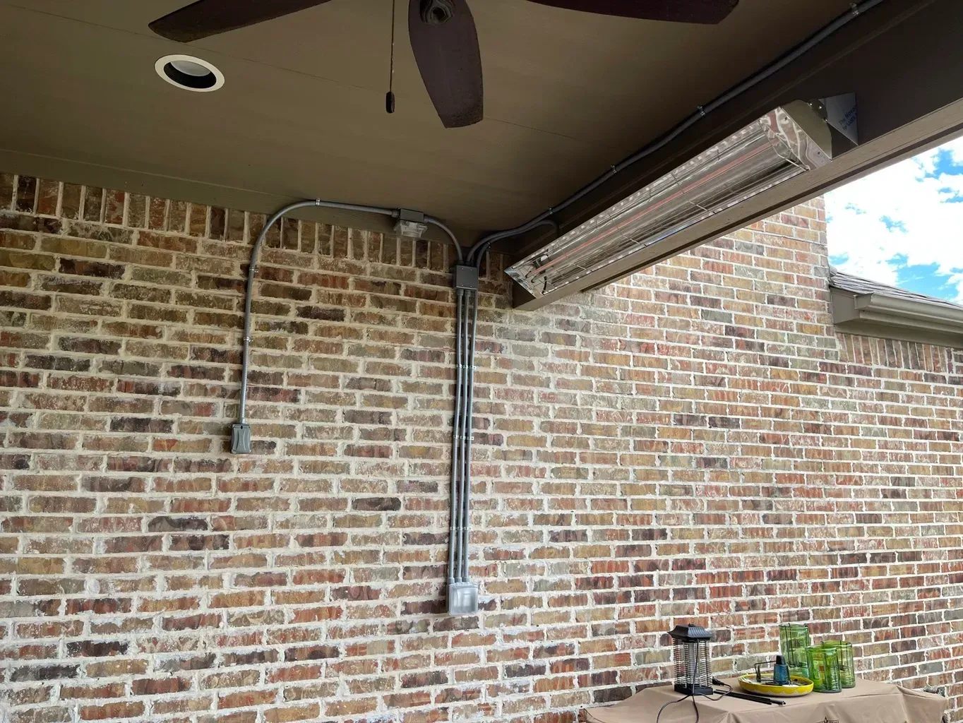 Brick wall with electrical conduit and a mounted outdoor heater.