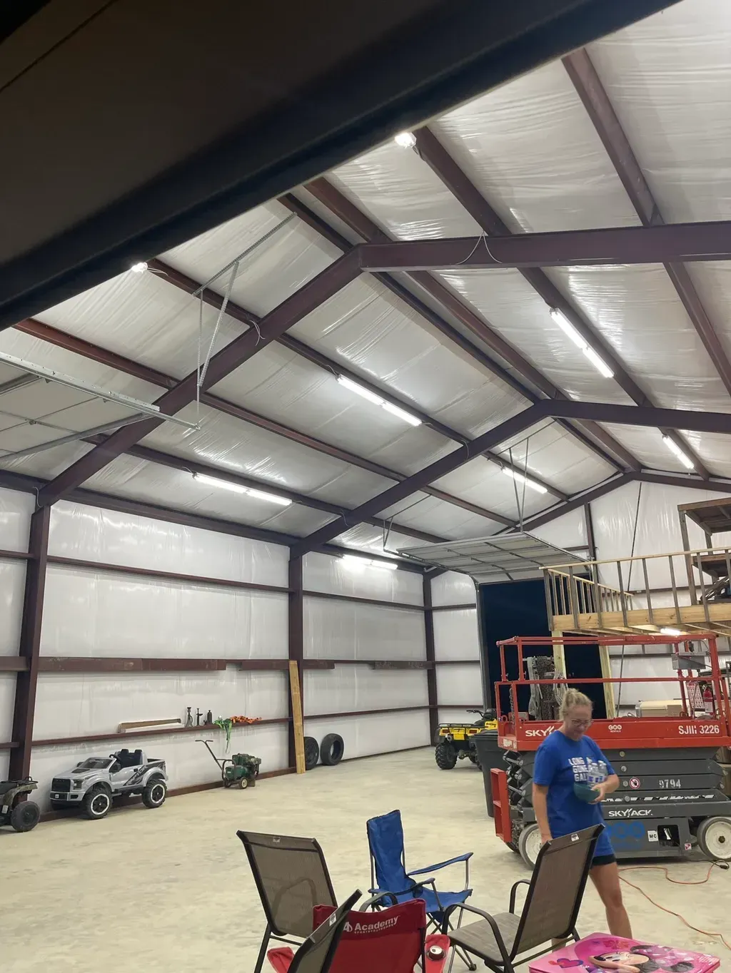 Inside a large garage with overhead lighting, a person and equipment are visible.