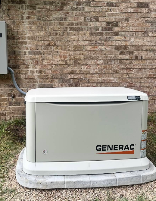 A beige Generac generator sits on a concrete pad next to a brick wall.