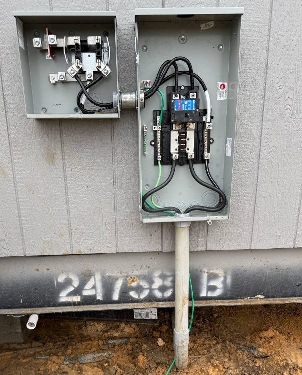 Outdoor electrical panel with meter box. Gray metal boxes with wiring attached to wooden siding.