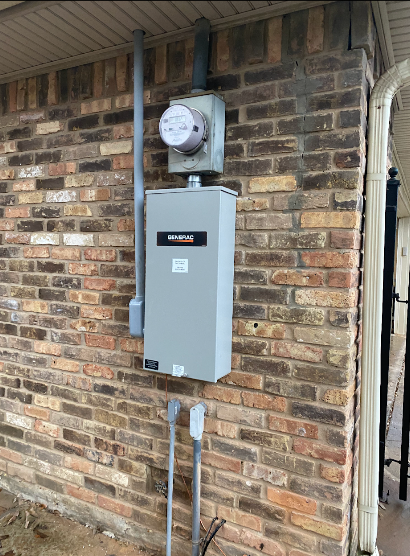 Electrical meter and panel mounted on a brick wall, with conduit and outlets below.