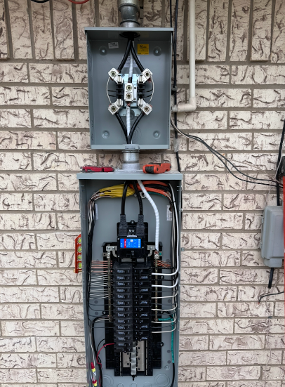 Electrical panel on brick wall with open cover, wires and conduit.