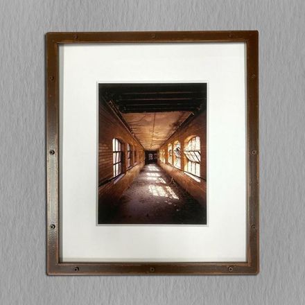 A picture of a hallway with lots of windows is framed on a wall.