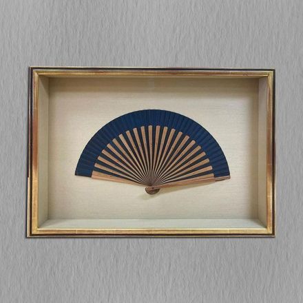 A picture of a fan in a frame on a wall.