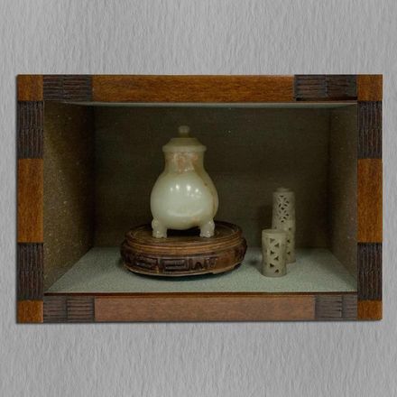 A picture of a vase and candles in a wooden frame