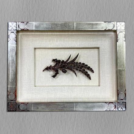 A picture of a dragon in a silver frame on a wall.