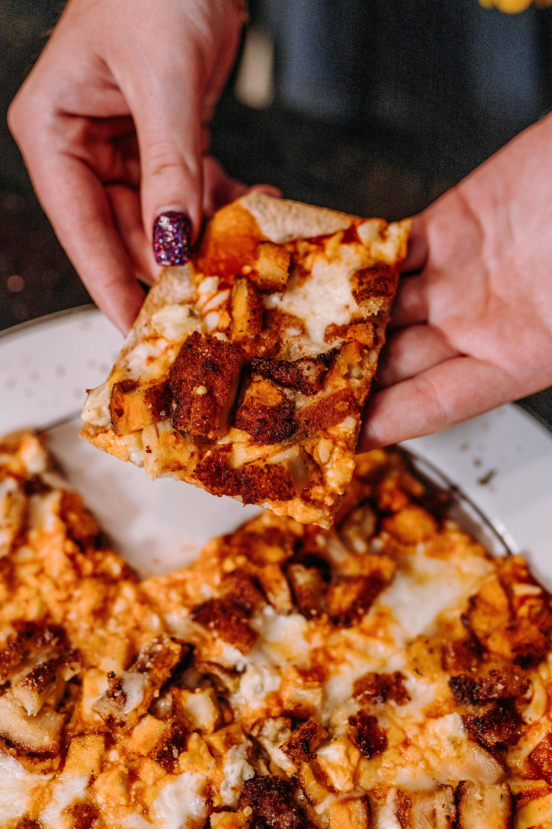 A person is holding a slice of pizza in their hand.