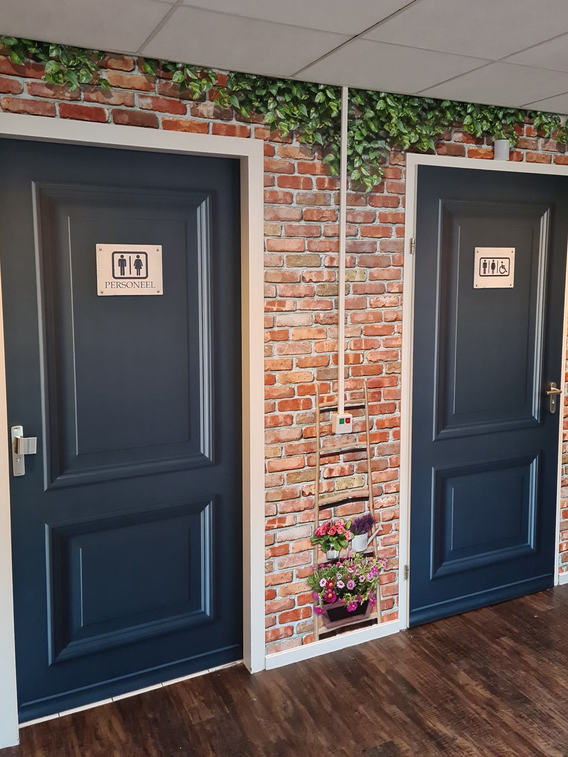 Een gang met twee deuren en een bakstenen muur