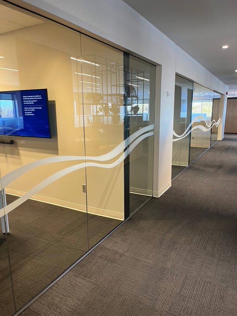 Un couloir avec des portes coulissantes en verre et une télévision au mur.