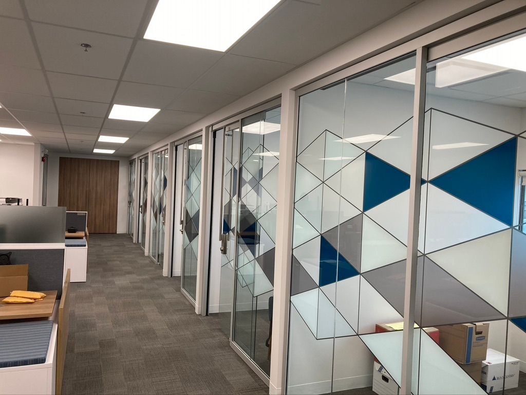 Une rangée de cabines dans un bureau avec des motifs géométriques sur les murs.