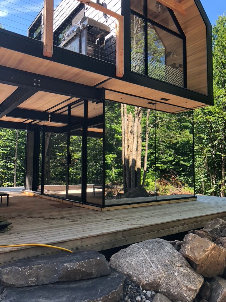 Une grande maison avec beaucoup de fenêtres est en construction dans les bois.