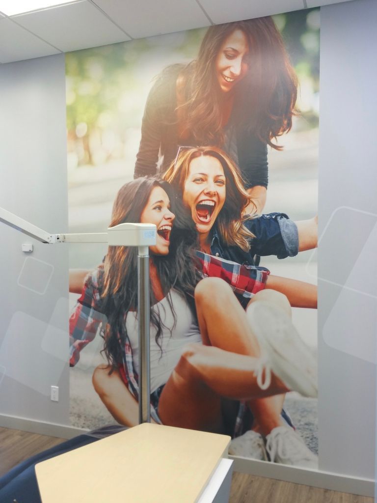 Un mur avec une photo de trois femmes qui rient dessus