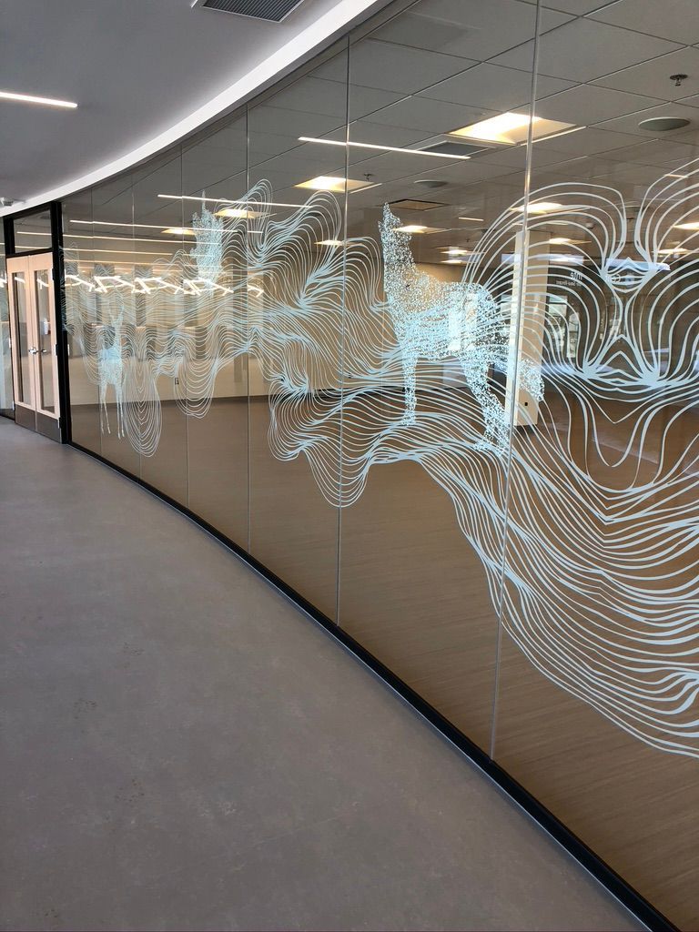 Un long couloir avec un mur de verre et le reflet du visage d'une personne dessus.