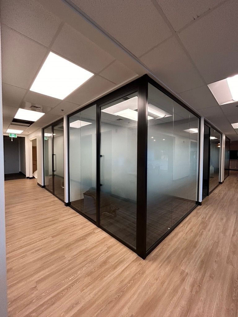 Un couloir avec beaucoup de murs en verre et un plancher en bois.