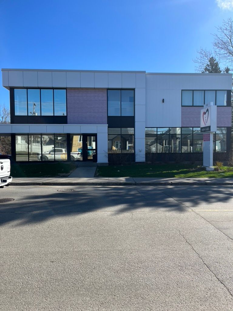 Un grand bâtiment avec beaucoup de fenêtres se trouve au coin d'une rue.