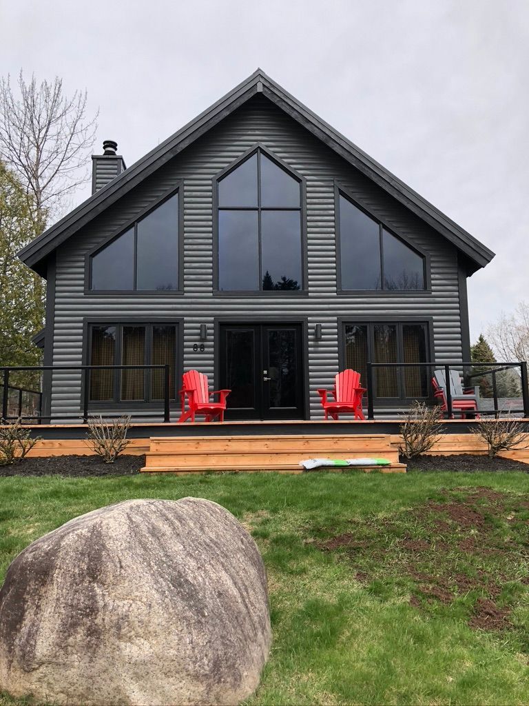 Une grande maison avec beaucoup de fenêtres et des chaises rouges sur la terrasse.
