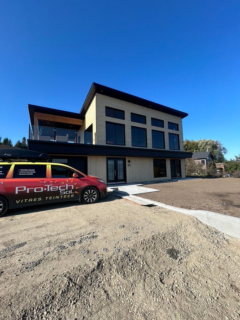 Une camionnette rouge est garée devant une grande maison.