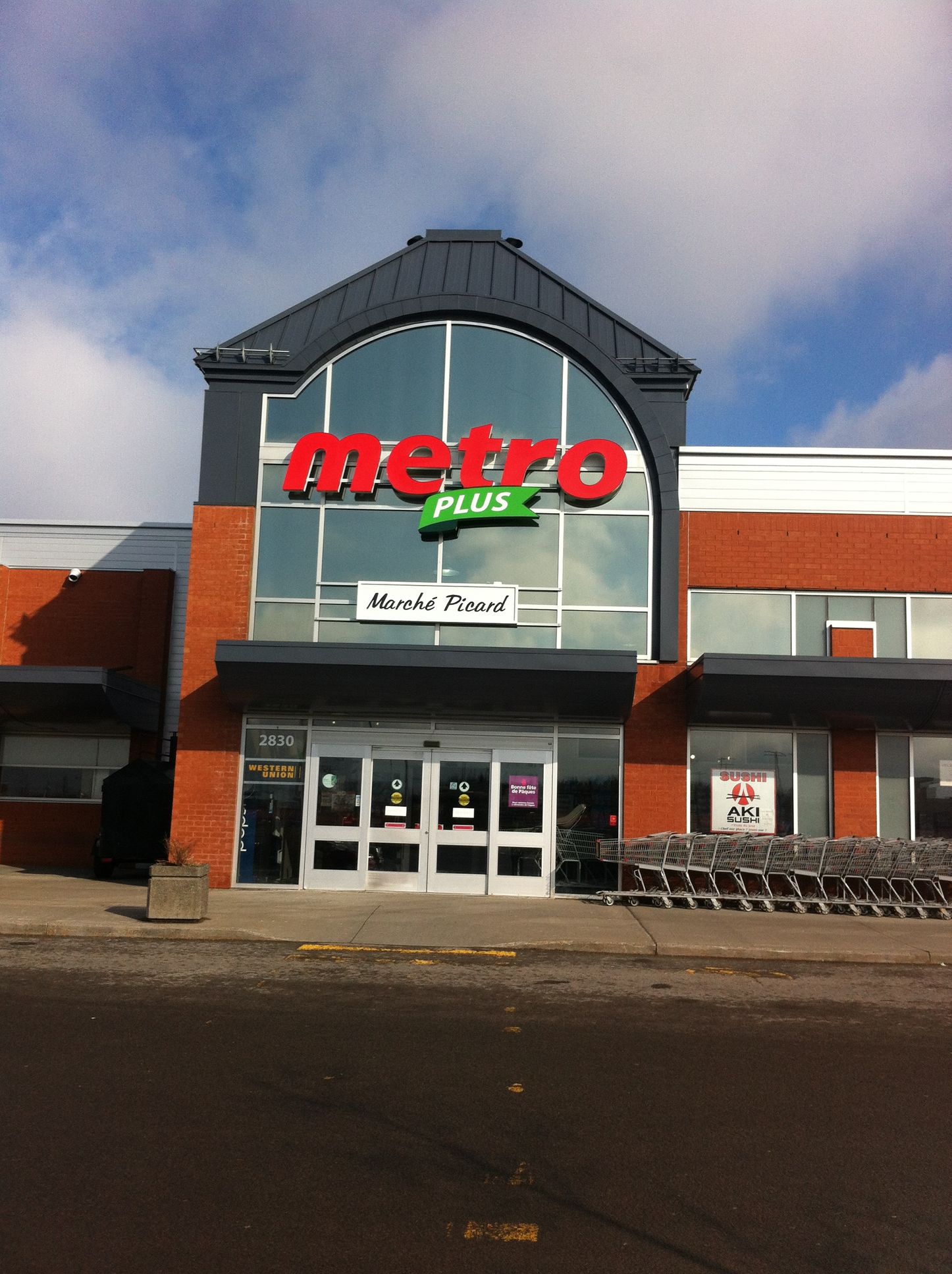 Un magasin Metro Plus avec une rangée de chariots devant lui