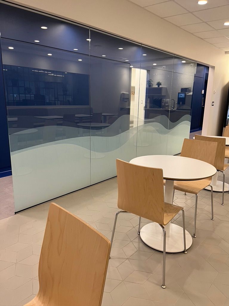 Une pièce avec une table et des chaises devant un mur en verre.