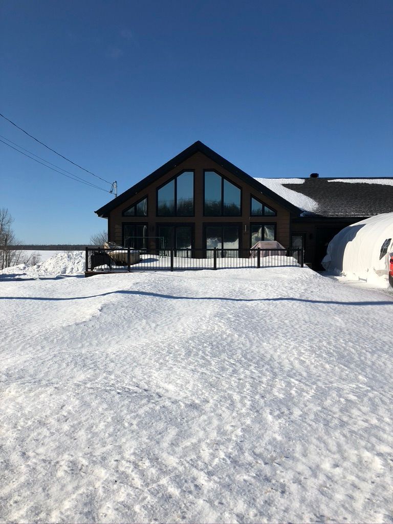 Une grande maison avec beaucoup de fenêtres est couverte de neige