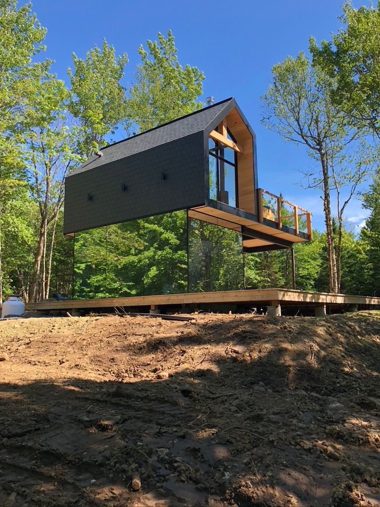Une petite maison est assise au sommet d'une colline de terre au milieu d'une forêt.