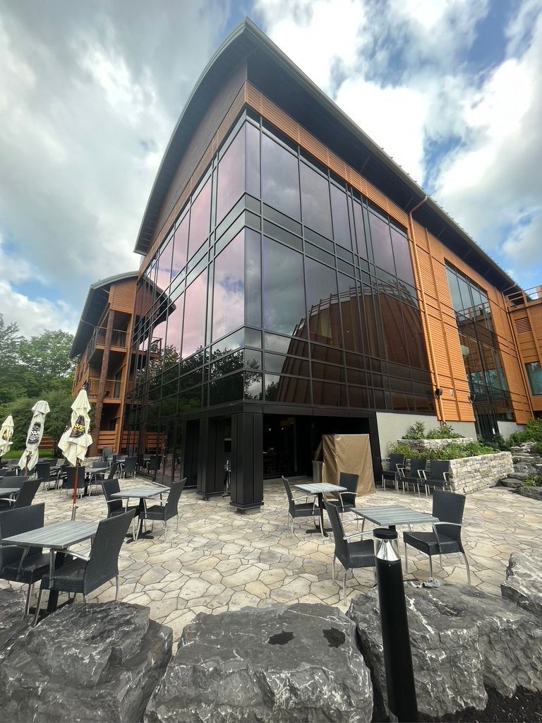 Un grand bâtiment avec beaucoup de fenêtres et de tables et de chaises devant lui.