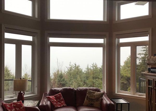 Un salon avec un canapé rouge et beaucoup de fenêtres