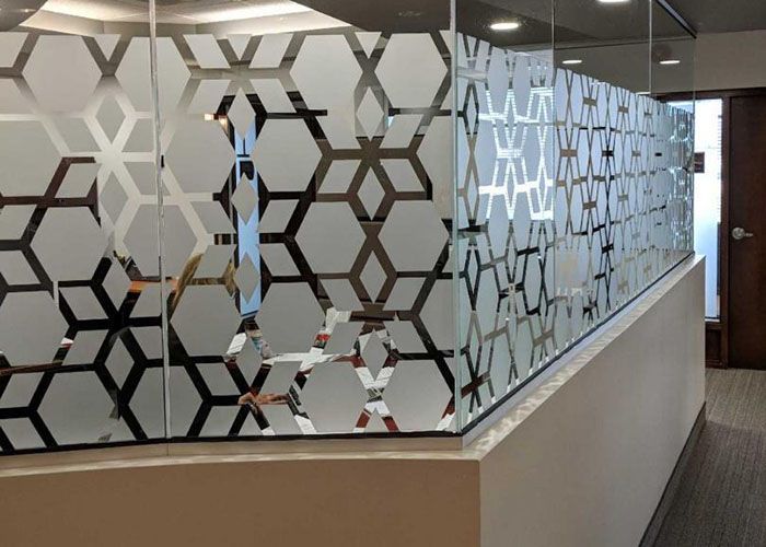 Un couloir avec un mur en verre avec un motif dessus.