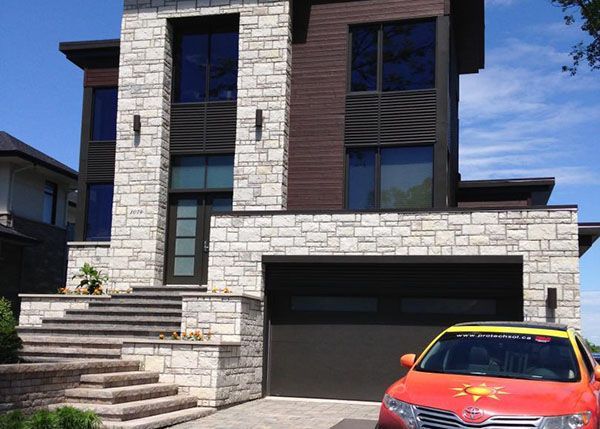 Une voiture rouge est garée devant une grande maison en briques.