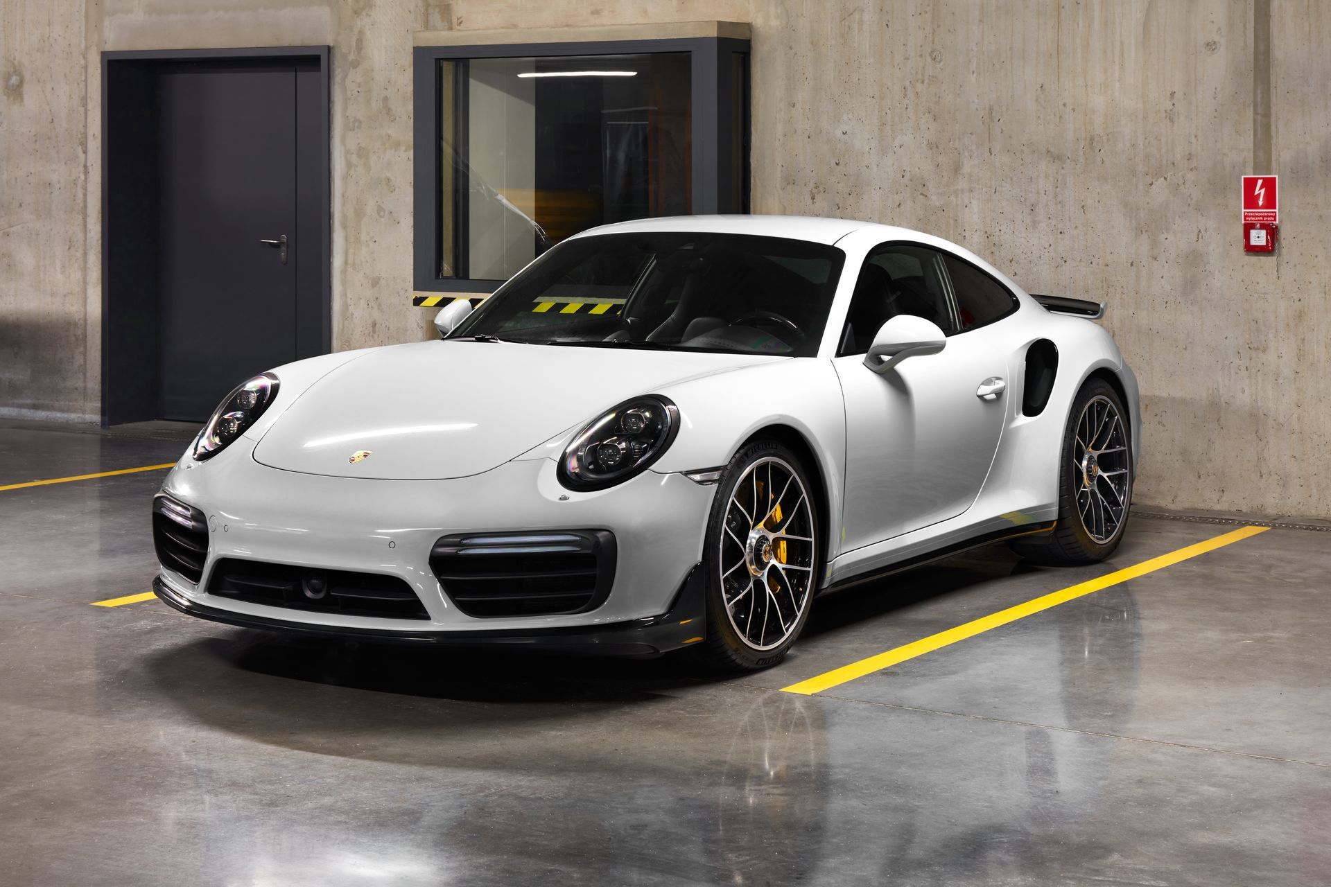 Une Porsche 911 turbo s blanche est garée sur un parking.