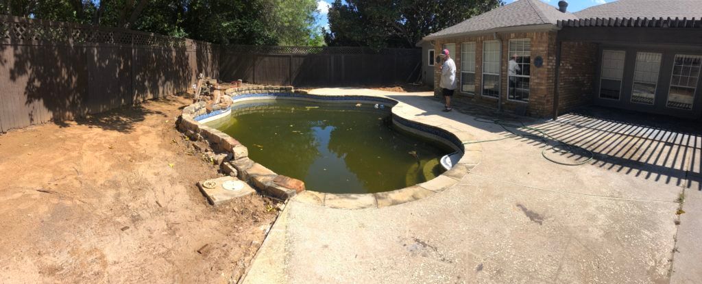 A large swimming pool is sitting in the backyard of a house.