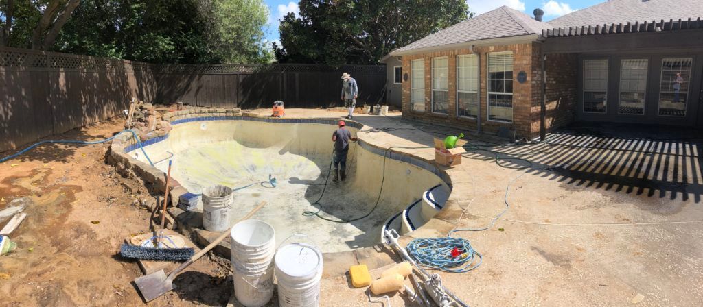 A swimming pool is being built in the backyard of a house.