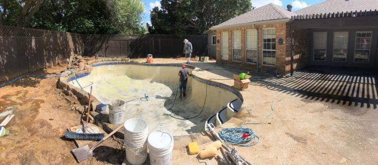 A swimming pool is being built in the backyard of a house.