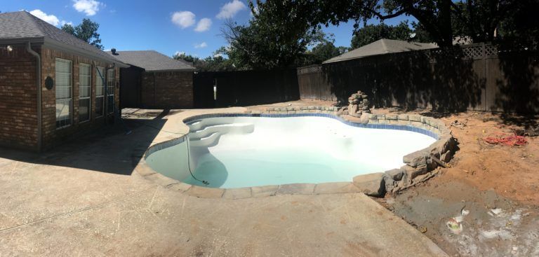 A large swimming pool in the backyard of a house.