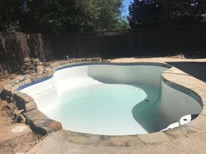 An empty swimming pool with a fence in the background