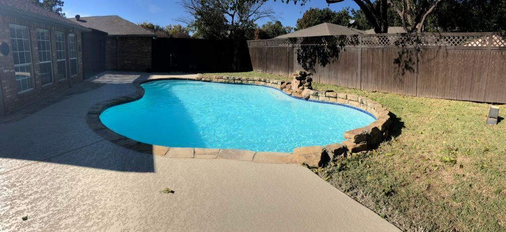 There is a large swimming pool in the backyard of a house.